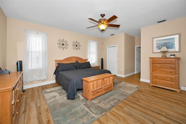 bedroom featuring visible vents, multiple windows, light wood-style flooring, and baseboards