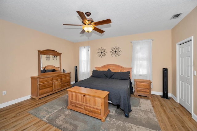 bedroom with a ceiling fan, visible vents, baseboards, and light wood-type flooring