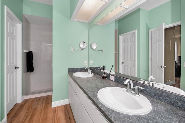 full bath featuring a sink, wood finished floors, and a tile shower