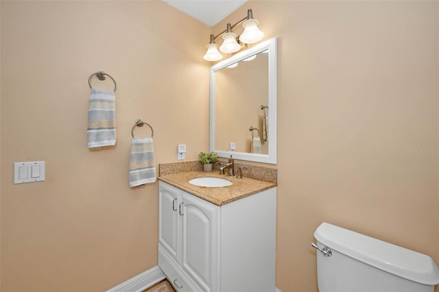 half bath featuring baseboards, toilet, and vanity