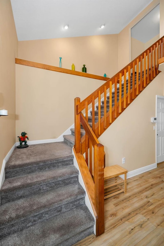 stairs featuring vaulted ceiling, baseboards, and wood finished floors