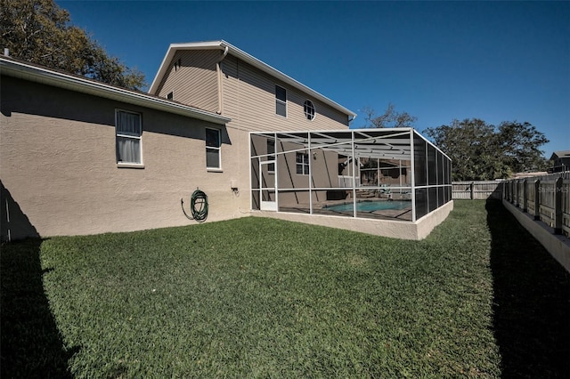 rear view of property featuring a fenced in pool, a fenced backyard, stucco siding, a lanai, and a lawn