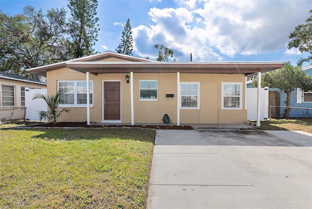 view of front of house with fence, a front lawn, and stucco siding