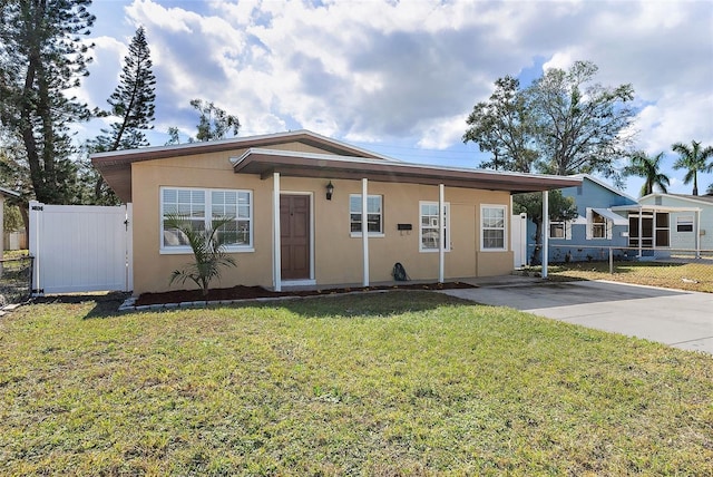 view of front of property featuring driveway, a front yard, fence, and stucco siding