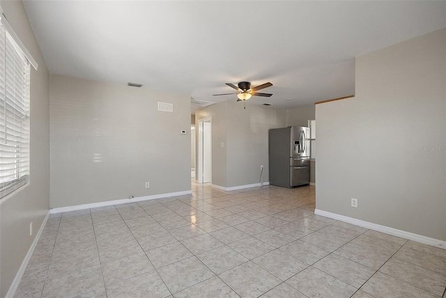 empty room featuring light tile patterned floors, ceiling fan, visible vents, and baseboards