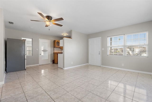 interior space featuring light tile patterned floors, baseboards, visible vents, and a ceiling fan