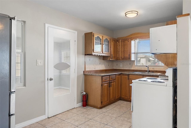 kitchen featuring brown cabinetry, white electric range, a sink, and light tile patterned floors