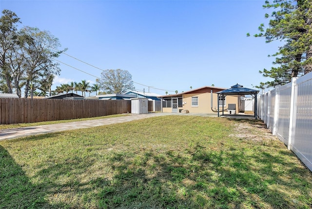 view of yard with a gazebo, a patio area, a shed, a fenced backyard, and an outdoor structure