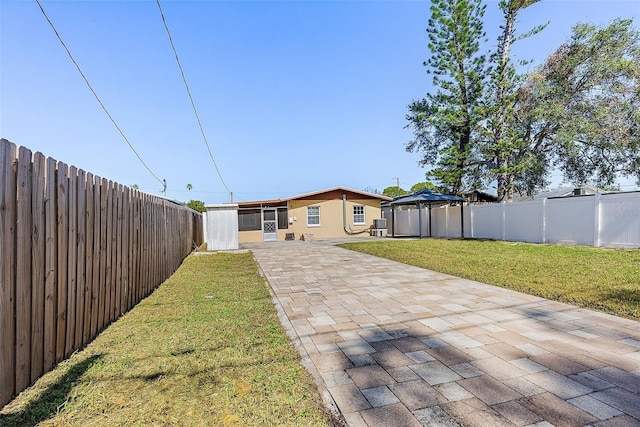 rear view of house with a fenced backyard, a patio, a lawn, and a gazebo