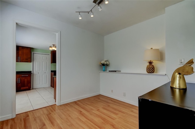 unfurnished dining area featuring track lighting, baseboards, and light wood-style floors