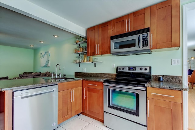 kitchen featuring open floor plan, light tile patterned floors, a peninsula, stainless steel appliances, and a sink