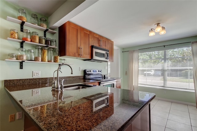 kitchen with a sink, open shelves, stainless steel appliances, light tile patterned flooring, and brown cabinetry