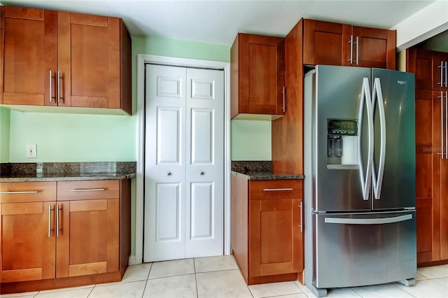 kitchen with dark stone counters, stainless steel fridge with ice dispenser, and brown cabinets