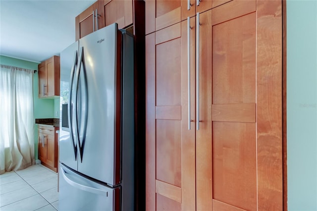 kitchen with light tile patterned flooring, stainless steel fridge, and dark countertops