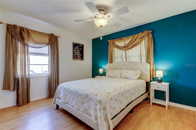 bedroom featuring light wood finished floors, a ceiling fan, and baseboards