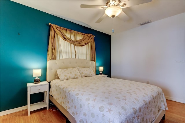 bedroom featuring visible vents, wood finished floors, baseboards, and ceiling fan