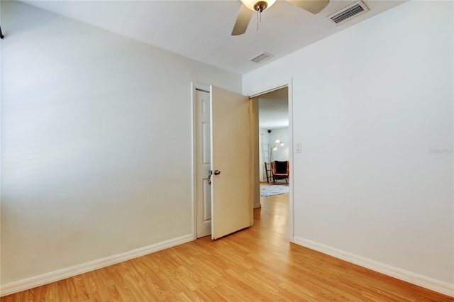 spare room featuring ceiling fan, light wood-style floors, visible vents, and baseboards