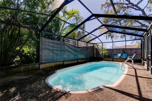 view of swimming pool featuring glass enclosure, a fenced in pool, a fenced backyard, and a patio area