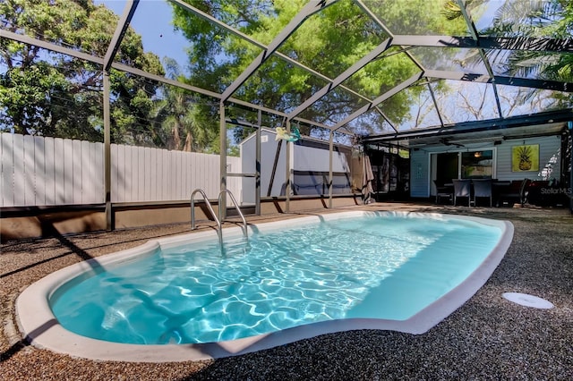 view of pool with glass enclosure, a storage shed, an outdoor structure, a fenced backyard, and a patio