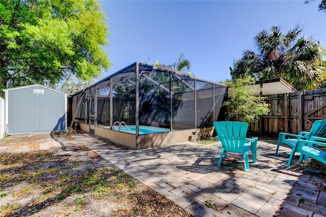 view of patio / terrace featuring glass enclosure, fence, a fenced in pool, an outdoor structure, and a storage shed