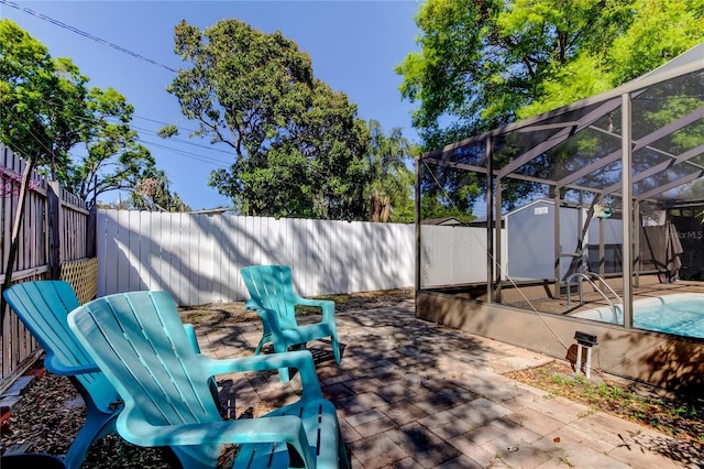 view of patio featuring an outbuilding, a fenced backyard, a shed, glass enclosure, and a fenced in pool