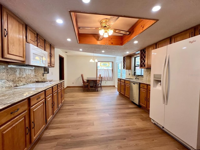1811 Tawnee Pl, Brandon, FL 33510 - kitchen with tasteful backsplash, white appliances, light wood-style floors, brown cabinets, and a tray ceiling