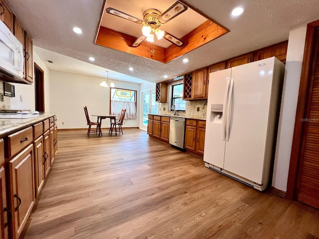 1811 Tawnee Pl, Brandon, FL 33510 - kitchen with white appliances, light wood-style flooring, brown cabinets, ceiling fan with notable chandelier, and baseboards