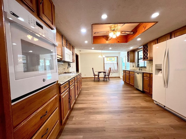 1811 Tawnee Pl, Brandon, FL 33510 - kitchen with ceiling fan, a raised ceiling, wood finished floors, white appliances, and brown cabinetry