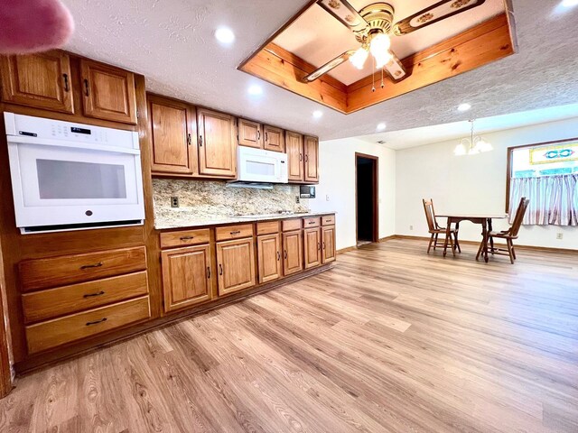 1811 Tawnee Pl, Brandon, FL 33510 - kitchen featuring white appliances, light wood-type flooring, a tray ceiling, and brown cabinetry