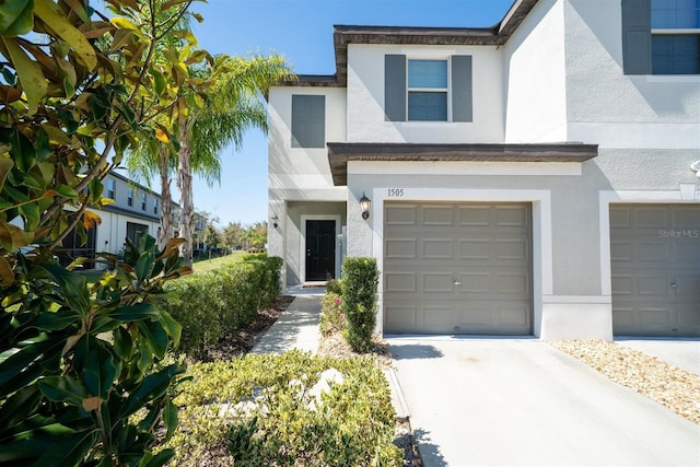 view of front of home with concrete driveway, an attached garage, and stucco siding