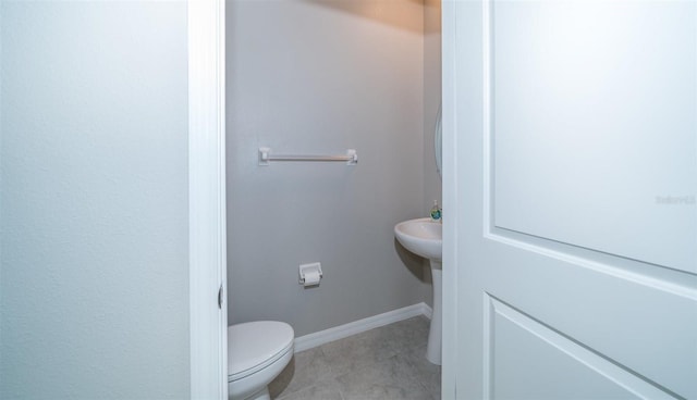 half bath featuring baseboards, toilet, and tile patterned floors