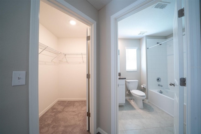 bathroom with baseboards, visible vents, toilet,  shower combination, and a walk in closet