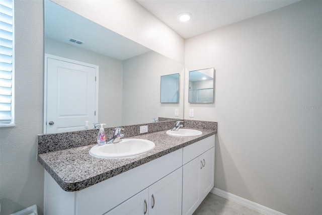 bathroom with double vanity, visible vents, baseboards, and a sink