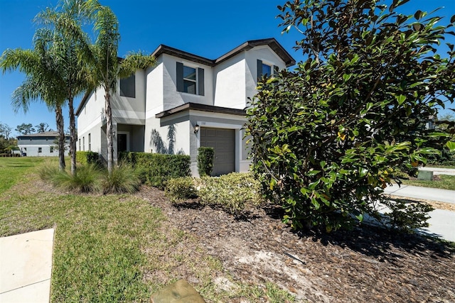 view of front of house featuring a garage, a front yard, and stucco siding