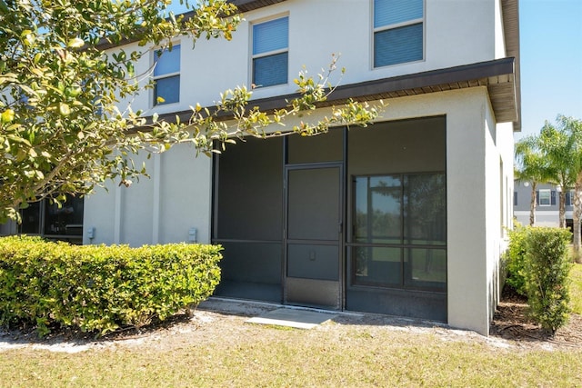 back of property with a sunroom and stucco siding