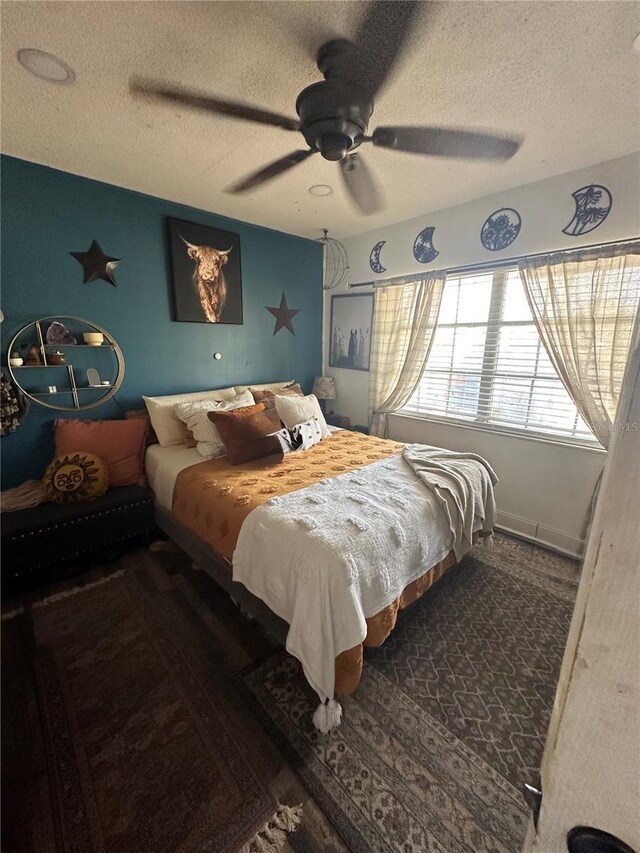 bedroom with a textured ceiling, wood finished floors, and a ceiling fan