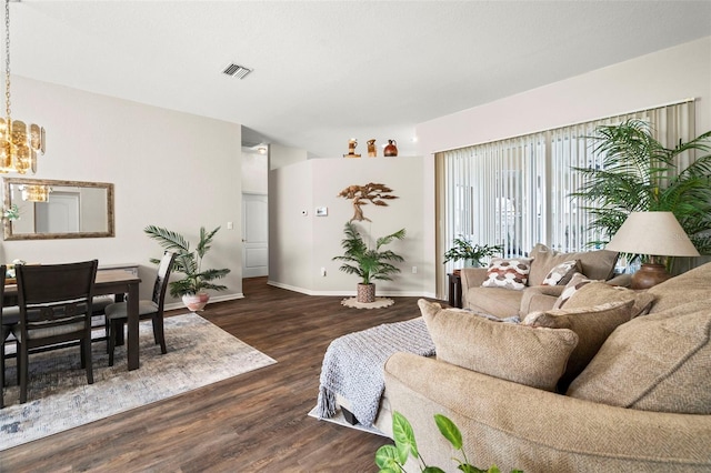 living area featuring visible vents, a notable chandelier, baseboards, and wood finished floors