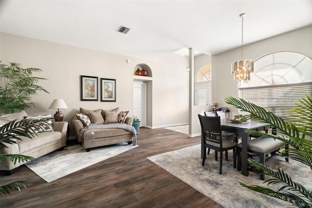 living room with dark wood-style floors, visible vents, a notable chandelier, and baseboards