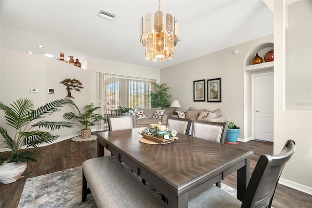 dining room featuring a chandelier, visible vents, baseboards, and wood finished floors