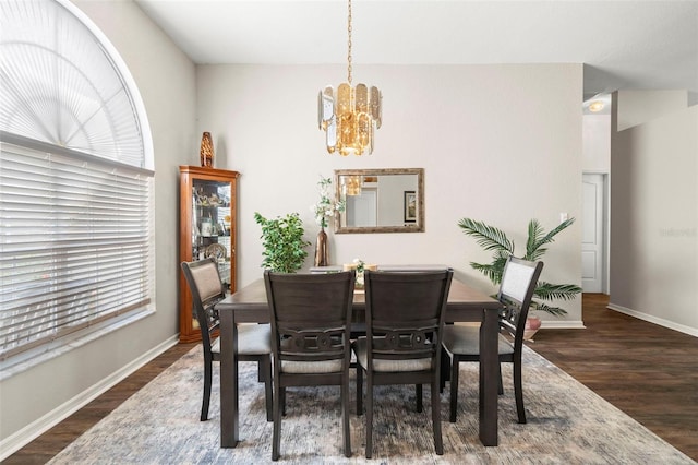 dining space featuring a chandelier, baseboards, and wood finished floors