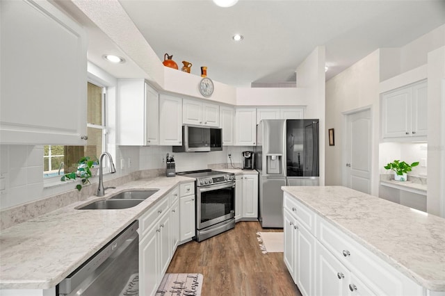 kitchen with dark wood-style flooring, backsplash, appliances with stainless steel finishes, white cabinets, and a sink