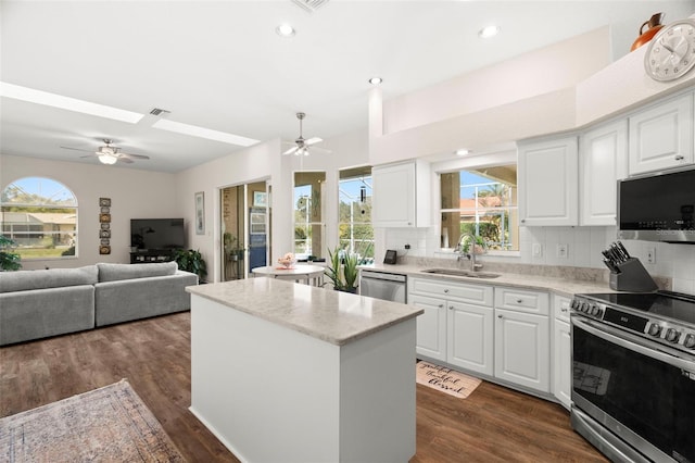 kitchen with a kitchen island, appliances with stainless steel finishes, dark wood-style flooring, a sink, and backsplash