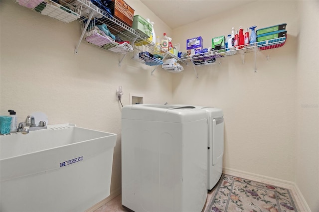 washroom with washing machine and dryer, laundry area, a sink, and baseboards