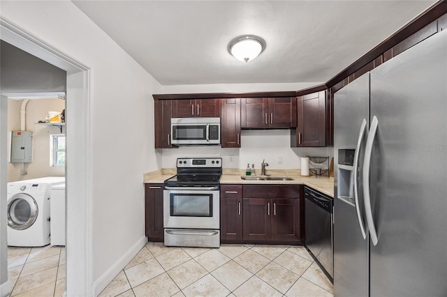 kitchen featuring electric panel, stainless steel appliances, light countertops, washing machine and dryer, and a sink