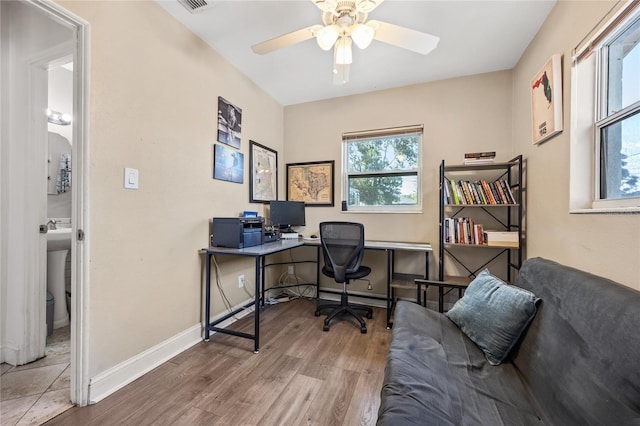 home office with a ceiling fan, visible vents, baseboards, and wood finished floors