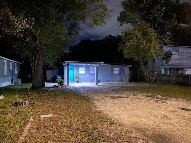 garage with fence, dirt driveway, and central air condition unit