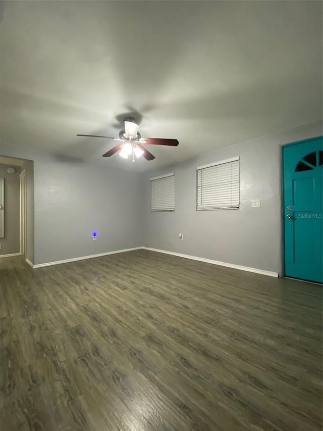 spare room with dark wood-style floors, ceiling fan, and baseboards