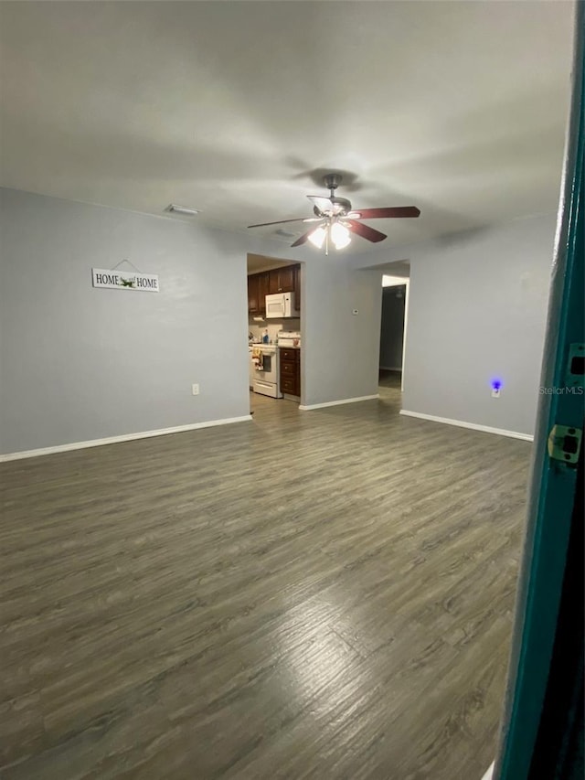 empty room featuring ceiling fan, dark wood-type flooring, and baseboards