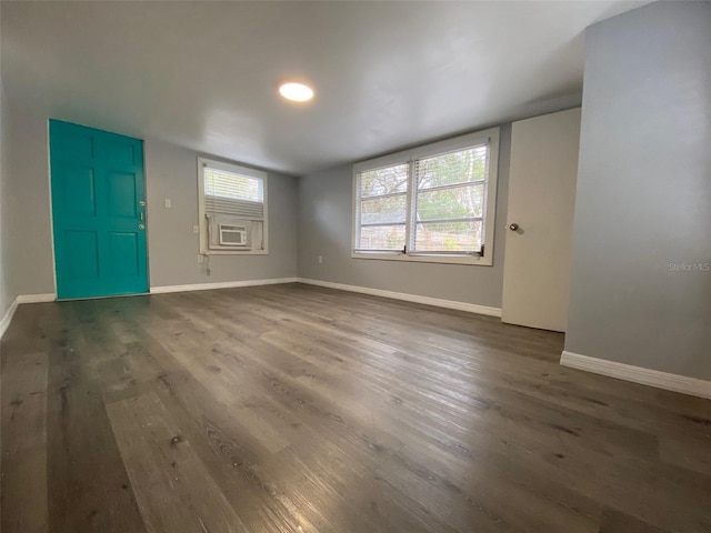 interior space featuring cooling unit, baseboards, and dark wood-type flooring