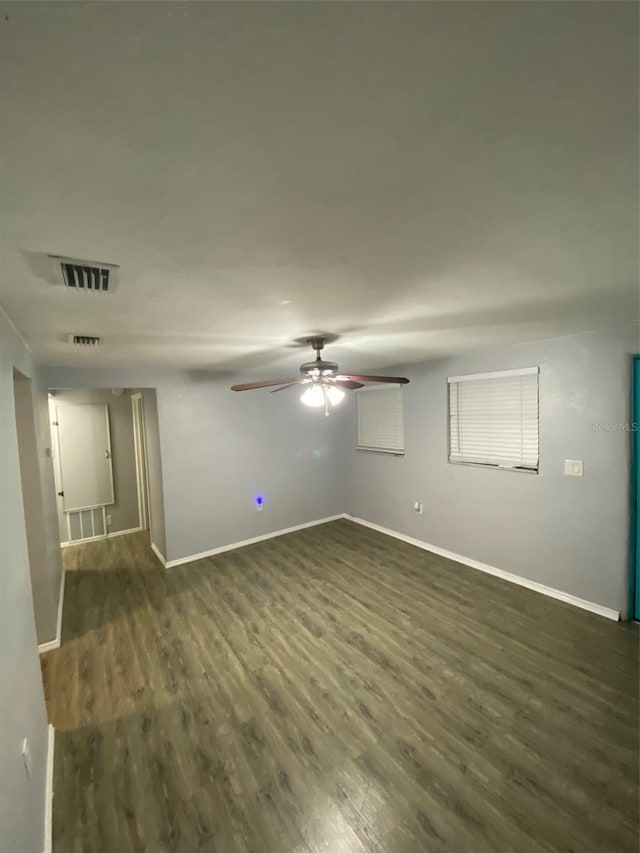 empty room featuring ceiling fan, baseboards, visible vents, and dark wood finished floors